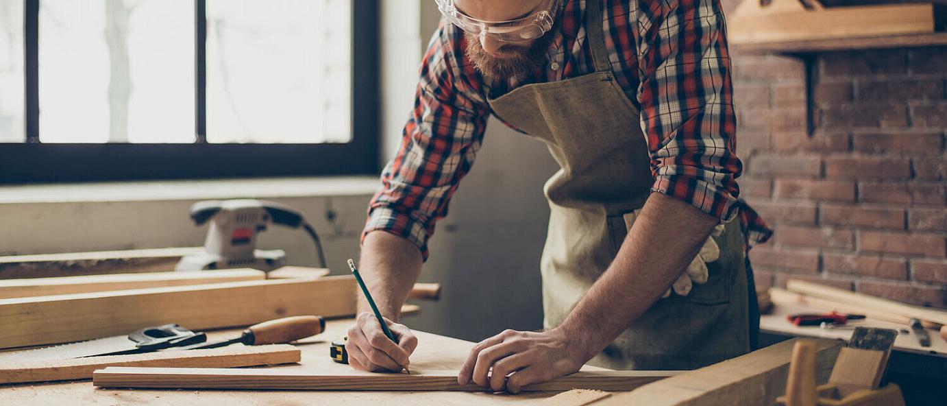 Handwerker mit Holzprojekt zeichnet Markierungen