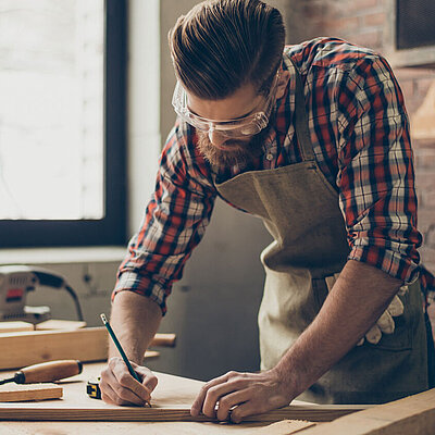 Handwerker mit Holzprojekt zeichnet Markierungen